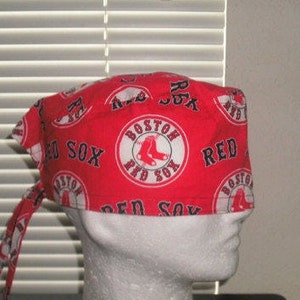 May include: Red and white surgical scrub hat with a repeating pattern of the Boston Red Sox logo. The logo features a red circle with the words "Boston Red Sox" and a white baseball shoe.