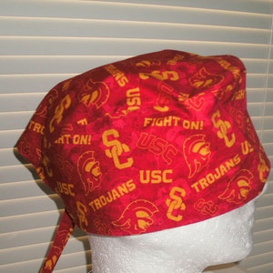 May include: Red and gold patterned surgical scrub hat with the words "USC Trojans" and "Fight On!" repeated throughout the design.