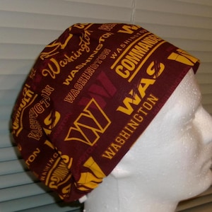 May include: A maroon and gold scrub hat with the words "Washington Commanders" and "W" repeated in a pattern.