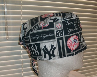 May include: A black and white patterned surgical scrub hat with the New York Yankees logo and baseball imagery. The hat has a tie on the back.