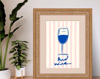 May include: Framed artwork with a blue wine glass illustration and the words "And wine..." in blue. The background has pink and white vertical stripes. The frame is gold.