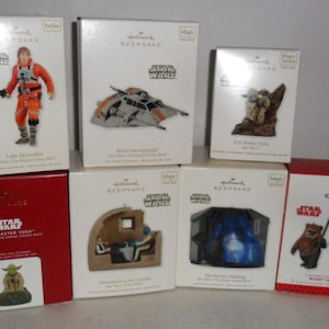 May include: A collection of Hallmark Keepsake Star Wars ornaments in their original boxes. The boxes feature images of characters and vehicles from the Star Wars franchise, including Luke Skywalker, Yoda, and the Millennium Falcon.