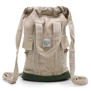 May include: A beige hemp backpack with a green base and adjustable shoulder straps. The bag has two small pockets and a drawstring closure at the top. The label reads "The Himalayan".