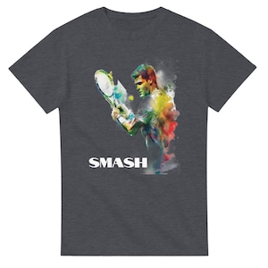 May include: Dark gray t-shirt featuring a colorful watercolor illustration of a tennis player mid-swing. The image includes a tennis racket, ball, and the word "SMASH" in white block letters at the bottom.