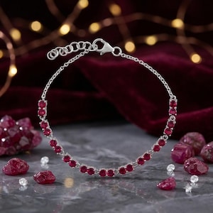 Peut inclure: Un bracelet en chaîne argentée orné d'une série de rubis ronds rouge foncé sertis dans des maillons métalliques individuels. Le bracelet comprend un fermoir mousqueton et une chaînette d'extension réglable avec plusieurs maillons circulaires.