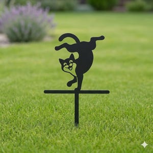 Op de afbeelding: Zwarte metalen katten tuinsteker. De kat is afgebeeld terwijl hij balanceert op een horizontale balk, met zijn lichaam gebogen en poten in de lucht. De paal is ontworpen om in de grond te worden gestoken, wat een grillige toets toevoegt.