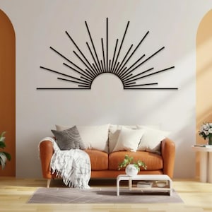 May include: A contemporary living room with an orange sofa, white cushions, and a black sunburst wall decoration. The room includes wooden shelves with plants and a small white table. The walls are painted in white and orange.