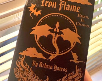 May include: A black book titled "Iron Flame" with orange illustrations of a dragon, clouds, and flames. The text "Burn. It. Down." and the author's name, Rebecca Yarros, are also featured on the cover.