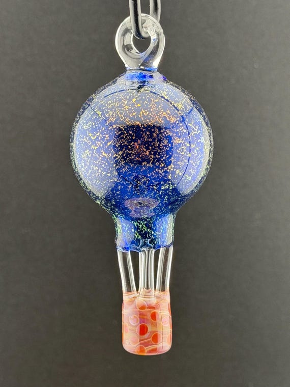 Hand-blown lampwork borosilicate hot air balloon with dichroic glass that shifts color in light — a tiny kinetic sculpture you hang in a window.