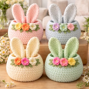 Pode incluir: Quatro cestos de coelhinho de crochê em cores pastel: rosa, azul claro, creme e verde menta. Cada cesto tem orelhas de coelho em pé e é decorado com uma grinalda floral. Perfeitos para a Páscoa.