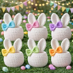 Könnte beinhalten: Sechs weiße Häschenkörbe aus Häkelarbeit mit bunten Schleifen. Die Körbe haben lange, aufrechte Ohren und sind mit blauen, rosa, lila, gelben, grünen und orangefarbenen Schleifen verziert. Die Körbe stehen auf einer grünen, grasbewachsenen Oberfläche mit bunten Ostereiern.