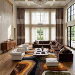 May include: A luxurious living room featuring a large brown sectional sofa, two white tufted armchairs, and a patterned area rug with shades of brown, yellow, and blue. The room has tall windows with sheer curtains and a crystal chandelier.