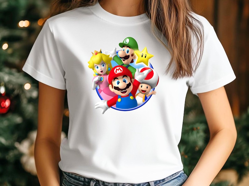 Op de afbeelding: Wit T-shirt met een kleurrijke afbeelding van Mario, Luigi, Princess Peach, Toad en een ster. De personages staan in een cirkel met een blauwe rand. Het shirt is gemaakt van een zacht, wit materiaal.