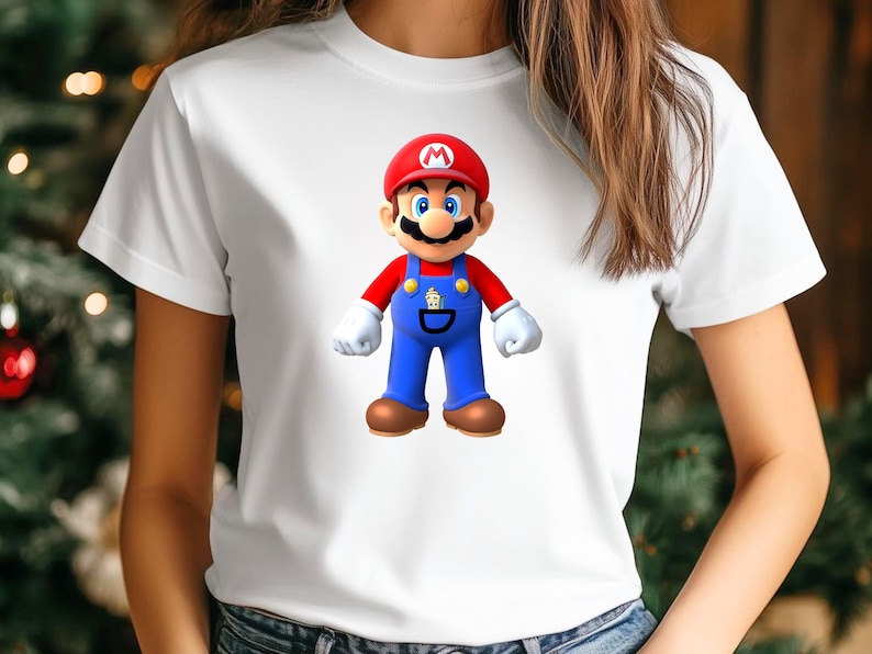 Op de afbeelding: Wit T-shirt met een afbeelding van het videogamepersonage Mario. Mario wordt getoond met zijn rode hoed, blauwe overall en bruine schoenen. Het T-shirt heeft een ronde hals.