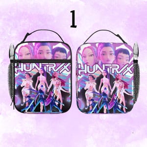 May include: Two lunch bags with a purple and pink design. The bags feature a graphic with the word "HUNTRAX" and images of stylized figures. Each bag has a black handle, a mesh side pocket, and a zippered front pocket.