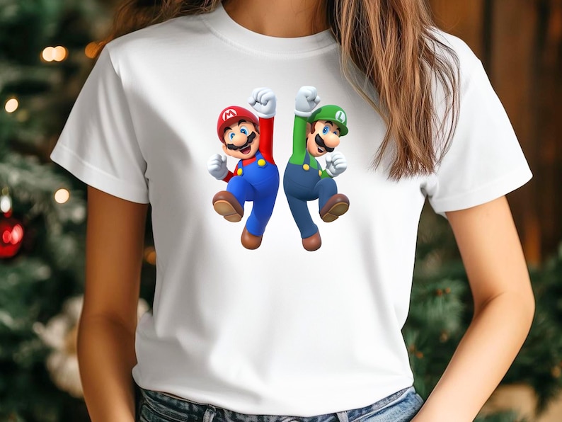 Op de afbeelding: Wit T-shirt met een afbeelding van Mario en Luigi, personages uit de Super Mario-videogameserie. Mario is in rood en blauw, en Luigi is in groen en blauw. Beiden springen met hun vuisten in de lucht.