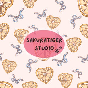 Könnte beinhalten: Ein sich wiederholendes Muster aus herzförmigen und kreisförmigen Orangenscheiben mit gelben und weißen Details sowie hellblauen Schleifen auf hellrosa Hintergrund. Der Text "SAKURATIGER STUDIO" befindet sich in einem rosa Oval.