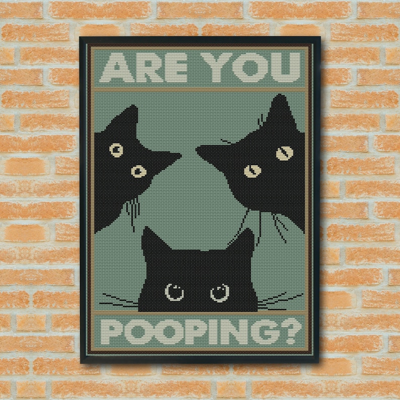 May include: A framed cross-stitch wall art piece featuring three black cat silhouettes on a sage green background. The text ARE YOU POOPING? is printed in a block font at the top and bottom. The cats have visible eyes and whiskers.