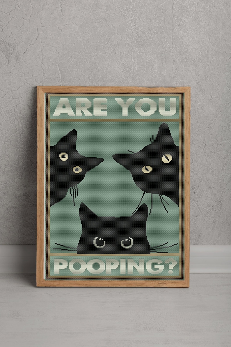 May include: A framed cross-stitch wall art piece featuring three black cats peering from the edges of a sage green background. The text ARE YOU is printed in white at the top, and the word POOPING? is printed in white at the bottom of the design.