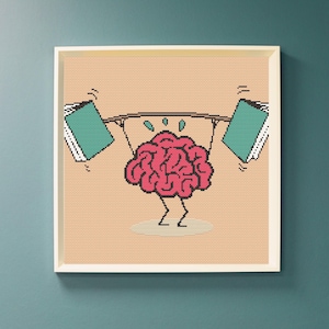 Peut inclure: Une œuvre d'art encadrée au point de croix représente un cerveau rose soulevant deux livres comme des poids. Le cerveau a des jambes et transpire. Le fond est beige et le cadre est blanc.