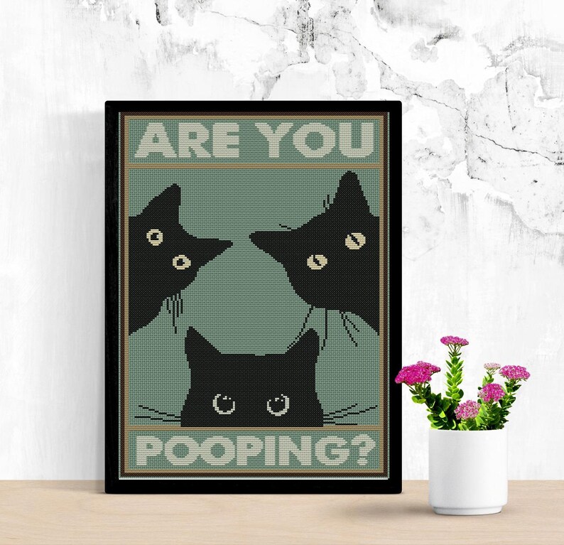 May include: A framed cross-stitch wall art piece featuring three black cat silhouettes against a muted sage green background. The text ARE YOU POOPING? is printed in white block letters at the top and bottom of the design within a dark border.