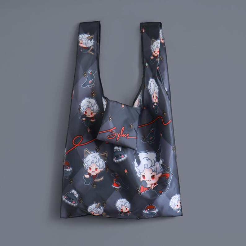 May include: A black reusable shopping bag with a white and red cartoon character design. The bag features a small pocket with the word "Sylus" written in red.