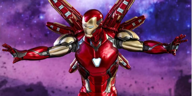 May include: A red and gold Iron Man action figure with outstretched arms and wing-like attachments. The figure has a metallic finish and is set against a purple and blue background, suggesting a space theme.