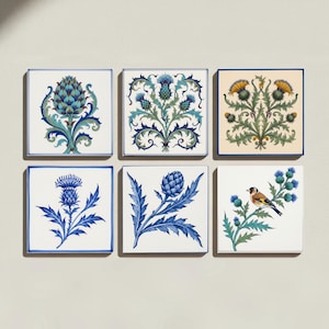May include: A set of six square ceramic tiles featuring botanical illustrations of thistles and artichokes in blue, green, and yellow tones. One tile depicts a small bird perched on a thistle branch. Each tile has a clean white background.