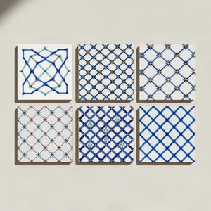 May include: A set of six square ceramic tiles arranged in two rows of three. Each tile features a distinct white background with blue, green, and yellow geometric patterns, including diamond grids, floral accents, and interconnected linear designs.