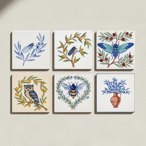 May include: A set of six square ceramic tiles featuring hand-painted illustrations. Designs include a blue cicada on olive branches, a cicada on a fruit branch, a large blue cicada, an owl on an olive branch, a bee in a wreath, and a terracotta vase.