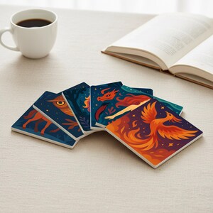 Può includere: Un set di cinque sottobicchieri quadrati in ceramica con illustrazioni a tema fantasy. Ogni sottobicchiere presenta un design diverso, tra cui una volpe, un gufo, un drago e una fenice, in colori vivaci su sfondo blu scuro. Una tazza da caffè bianca e un libro aperto sono anche nell'immagine.