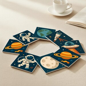 Puede incluir: Un conjunto de ocho posavasos cuadrados con ilustraciones temáticas del espacio. Cada posavasos presenta un diseño diferente, incluyendo un astronauta, planetas, la Tierra, un telescopio y un OVNI, todo sobre un fondo azul oscuro estrellado.