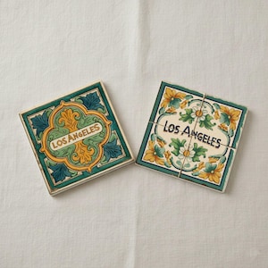 May include: Two decorative ceramic tiles with floral designs and the text "LOS ANGELES". One tile is whole, the other is divided into four pieces. The tiles feature green, yellow, and blue colors.