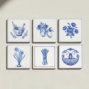 May include: A set of six square white ceramic tiles featuring blue illustrations. The designs include a mortar and pestle with herbs, a fennel bulb and lemon, a cluster of flowers, daffodils, a bundle of asparagus, and a windmill in a field.