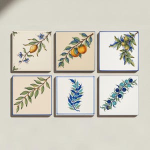 May include: A set of six square ceramic tiles arranged in two rows. Each tile features a unique botanical illustration, including yellow lemons, orange persimmons, green olives, leafy branches, and clusters of blue berries on white or cream backgrounds.