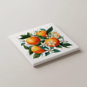 May include: Square white canvas art featuring a watercolour illustration of oranges, green leaves, and white blossoms. The artwork includes four whole oranges, a sliced orange, and small gold accents. The art piece is a decorative item.
