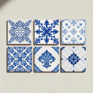 May include: A set of six square ceramic tiles featuring a variety of blue and white patterns. Each tile displays distinct symmetrical floral and geometric motifs, including intricate scrollwork, fleur-de-lis designs, and grid-based arrangements.