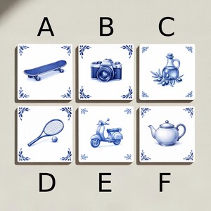 May include: Set of six square ceramic tiles with blue and white illustrations. Designs include a skateboard, camera, olive oil bottle, tennis racket and ball, scooter, and teapot. Each tile has a blue floral border.