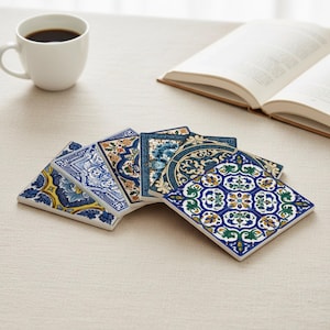 K&ouml;nnte beinhalten: Eine Sammlung dekorativer Keramikuntersetzer mit aufwendigen blauen, gelben und gr&uuml;nen Blumenmustern. Die Untersetzer sind quadratisch und f&auml;cherf&ouml;rmig angeordnet. Eine wei&szlig;e Kaffeetasse und ein offenes Buch befinden sich im Hintergrund.