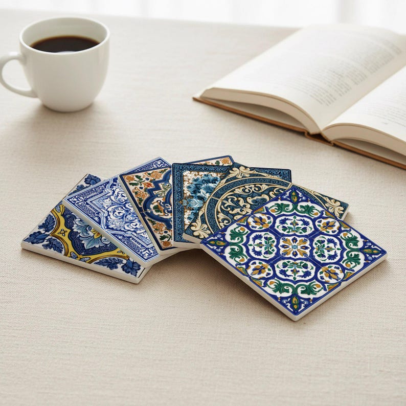 K&ouml;nnte beinhalten: Eine Sammlung dekorativer Keramikuntersetzer mit aufwendigen blauen, gelben und gr&uuml;nen Blumenmustern. Die Untersetzer sind quadratisch und f&auml;cherf&ouml;rmig angeordnet. Eine wei&szlig;e Kaffeetasse und ein offenes Buch befinden sich im Hintergrund.