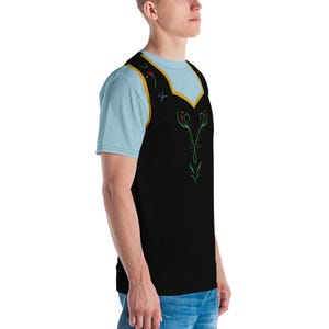 Pu&ograve; includere: Una t-shirt nera e blu con un design dorato e verde sul davanti. Il design presenta un motivo floreale stilizzato con una forma di cuore al centro.