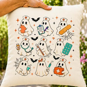 May include: A square off-white throw pillow featuring a repeating pattern of nine cartoon ghosts dressed as nurses. The ghosts hold medical items like a clipboard, thermometer, syringe, and first aid kit, accented by small bats, hearts, and stars.