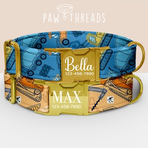 May include: Two personalized dog collars. The top collar is blue with construction vehicle graphics and the name "Bella" in white. The bottom collar is tan with construction vehicle graphics and the name "MAX" in white. Both collars have gold-colored hardware.