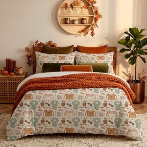 Può includere: Un set di biancheria da letto con un motivo ripetuto di borse, tazze da caffè, sciarpe e occhiali da sole su sfondo bianco. Il set include un copripiumino e due federe, arricchito da una coperta arancione in maglia grossa.
