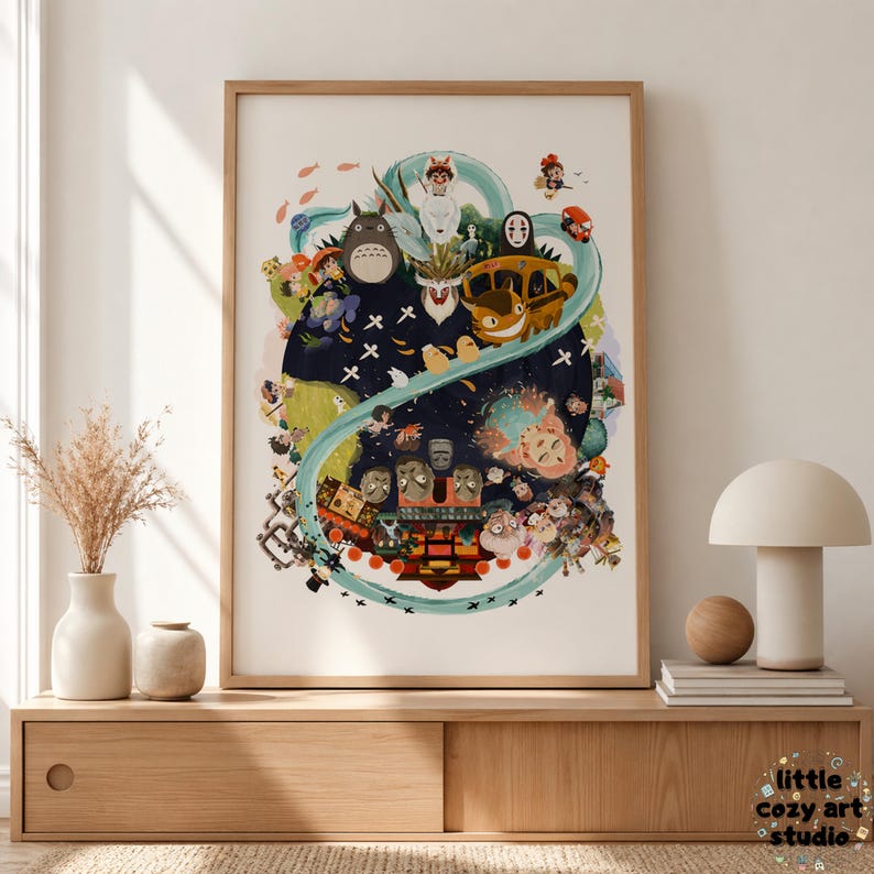 Op de afbeelding: Een ingelijste kunstprint met een kleurrijke illustratie van personages uit een Japanse animatiefilm. Het kunstwerk bevat verschillende wezens en een gele bus, tegen een donkerblauwe achtergrond met een wervelend ontwerp. De print wordt tentoongesteld op een houten kast.