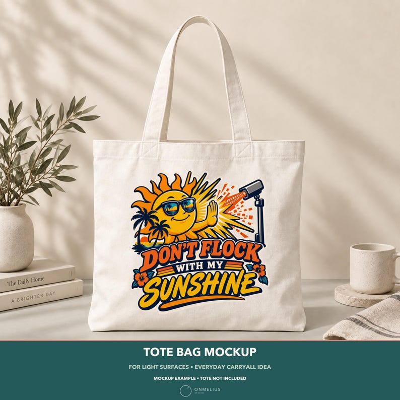 May include: A cream-colored canvas tote bag featuring a graphic of a smiling sun wearing sunglasses, palm trees, and a camera on a tripod. The text reads "DON'T FLOCK WITH MY SUNSHINE" in bold, colorful lettering with orange and blue accents.