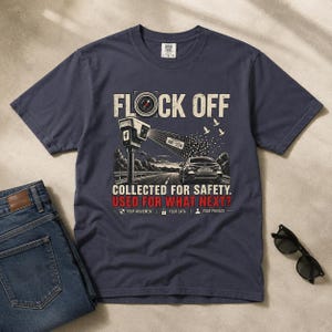 Puede incluir: Una camiseta azul marino de manga corta con un estampado gráfico de una cámara de vigilancia escaneando un coche en una carretera. El texto dice FLOCK OFF, COLLECTED FOR SAFETY, USED FOR WHAT NEXT?, YOUR MOVEMENT, YOUR DATA, YOUR PRIVACY.