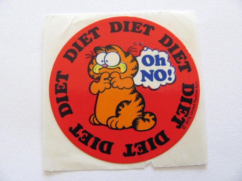 May include: A red circular sticker with the words "Diet" repeated around the edge. In the center is a cartoon orange cat with a thought bubble that says "Oh No!"  The text at the bottom reads "&copy; 1978 United Feature Syn."
