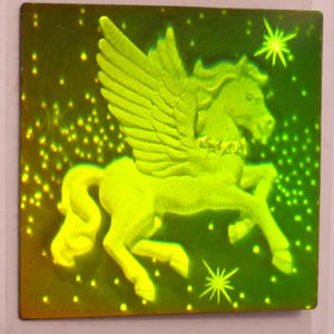 Puede incluir: Una pegatina hologr&aacute;fica verde que presenta un caballo alado con un collar dorado. El caballo se representa sobre un fondo verde oscuro con peque&ntilde;os puntos blancos.