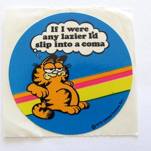 May include: A round sticker featuring Garfield the cat with a thought bubble that says "If I were any lazier I'd slip into a coma". The sticker has a blue background with a rainbow stripe and the copyright information "&copy; 1978 United Feature Syn."